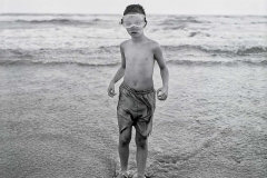 Young boy standing in ocean.