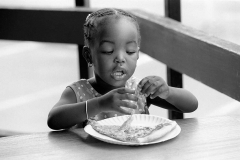 Young African American girl eating a slice of pizza.
