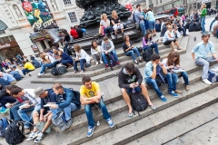 People sitting and resting on the steps of the Piccadilly Circus Monument Sculpture.