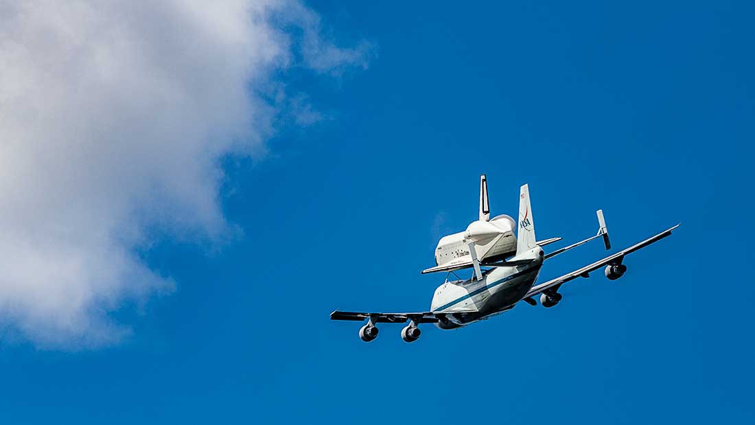 The Space Shuttle Enterprise flies piggy back on a jet in the sky.