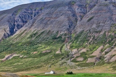 A tiny house sits by a mountain in Iceland.