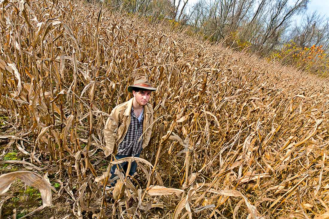 Young man standing in a field of corn.