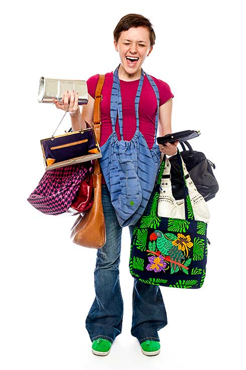 A female teenager poses with a bunch of purses and ladies and women's bags.