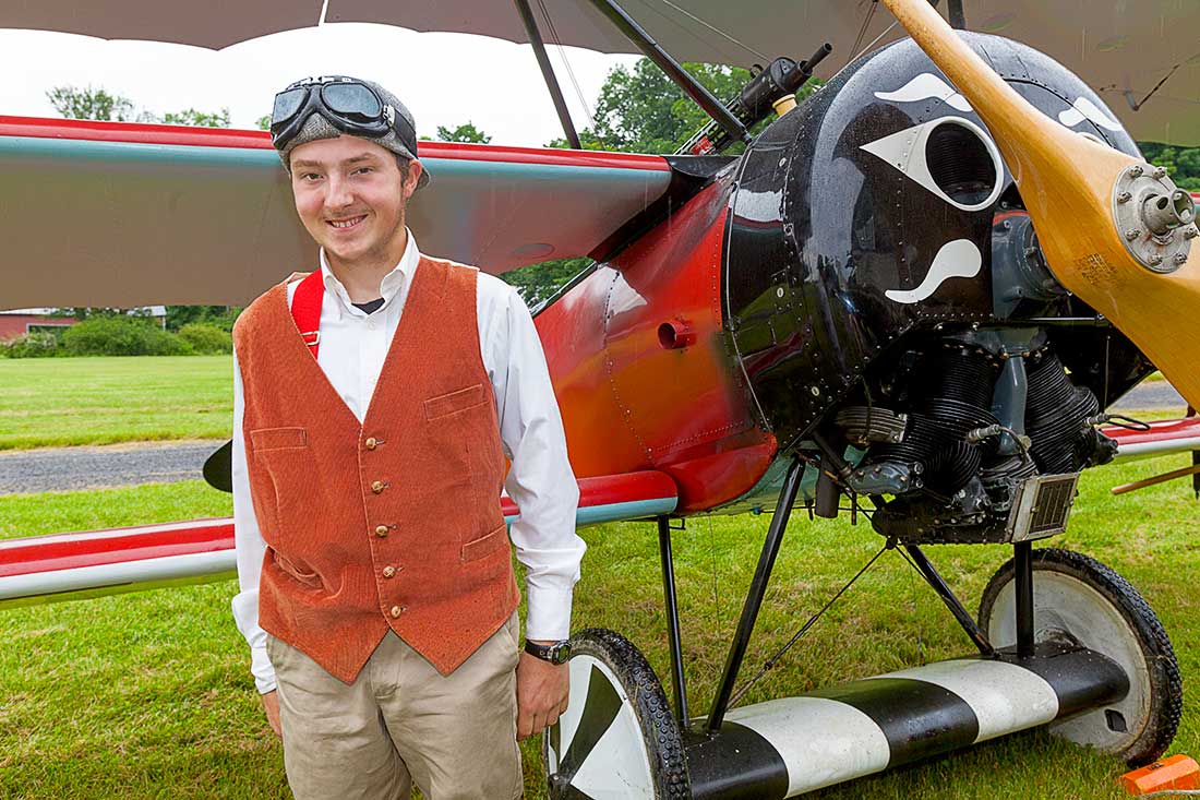 A pilot standing by an antique airplane.