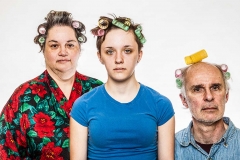 A man, a woman and a young woman wearing hair curlers.