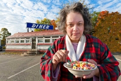 Woman eating cereal in front of a diner.