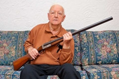 Elderly man holding a shotgun.